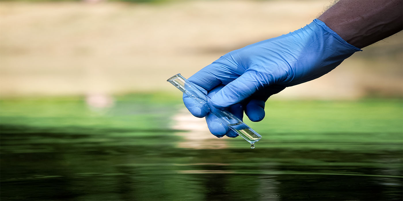 test tube sample of water being taken from stream